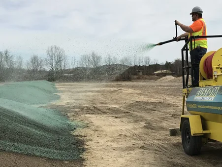 Custom Exterior Landscape crew hydroseeding after recent regrading of commercial property